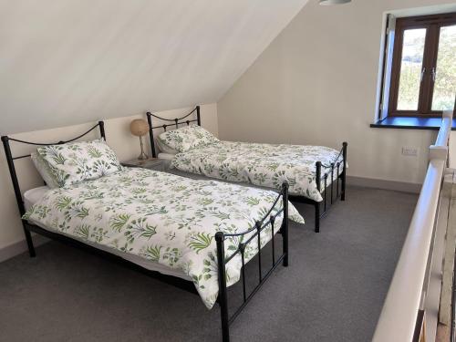 a bedroom with two beds and a window at Poachers Hut - Captivating 1-bed Cottage Shorwell in Shorwell