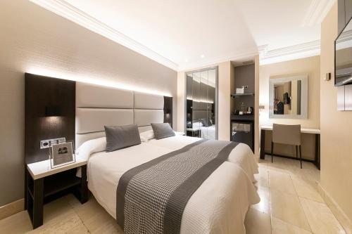 a bedroom with a large bed with a desk and a desk at Habitus Hotel Europa in Pamplona