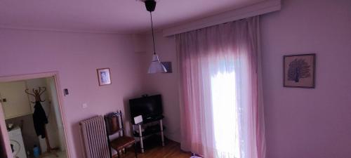 una sala de estar con una ventana con cortinas rosas en Quiet - Comfortable apartment 33sqm Pagrati Athens, en Atenas