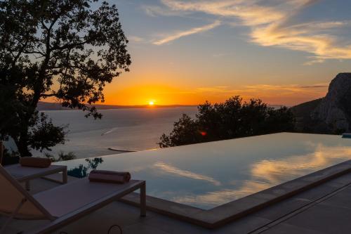 a pool with a sunset in the background at Luxury Villa La Mirada in Omiš