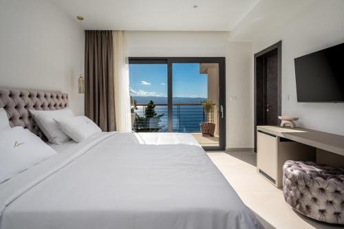a bedroom with a large white bed and a television at Luxury Villa La Mirada in Omiš