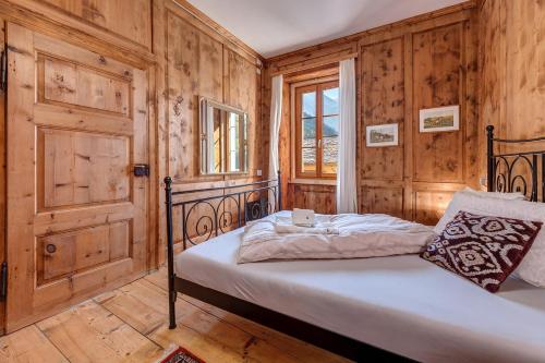a bedroom with a bed with wooden walls and a window at In val Bregaglia mille possibilità di benessere in Castasegna