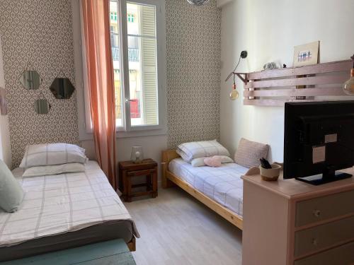 - une chambre avec 2 lits, une télévision et une fenêtre dans l'établissement appartement cosy, à Nice