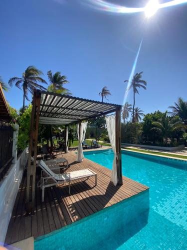 una piscina con pérgola y sillas junto a una piscina en BEACH VILLA Camurupim en Guajiru