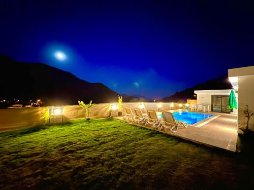 un patio con sillas y una piscina por la noche en Sapphire, en Fethiye