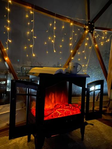 a table with a fireplace in a tent with lights at Phalesia Glamping Otel in Sapanca