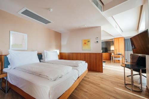 um quarto de hotel com uma cama grande com lençóis brancos em Peakture Hotel em Bucareste
