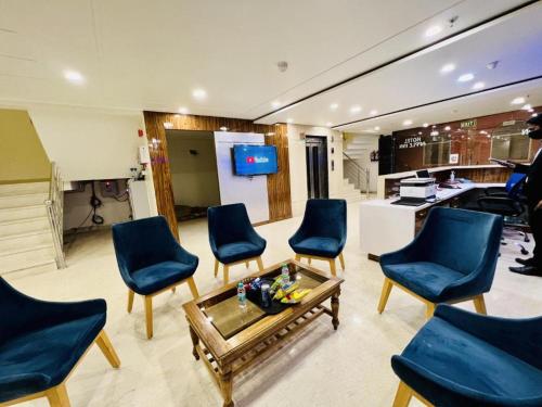 Hotel Apple Inn n Suites, New Delhi في نيودلهي: غرفة معيشة مع كراسي زرقاء وطاولة قهوة