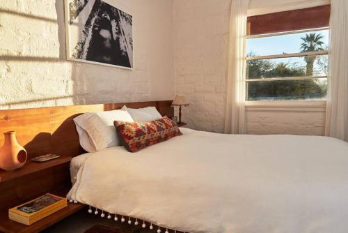 een slaapkamer met een bed en een raam bij Casa de la Muxer - 940s Adobe - Hot Tub - Cowboy Pool in Twentynine Palms