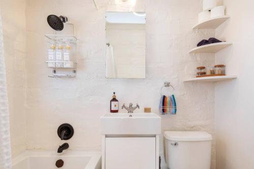 een witte badkamer met een wastafel en een toilet bij Casa de la Muxer - 940s Adobe - Hot Tub - Cowboy Pool in Twentynine Palms