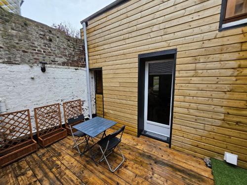 une terrasse en bois avec une table et des chaises. dans l'établissement ENTRE 2 VAGUES, à Mers-les-Bains