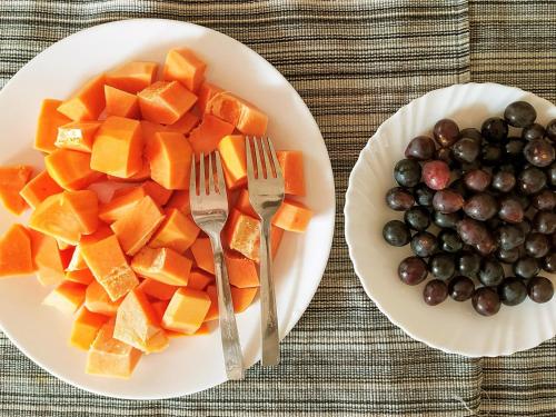 two plates of fruit and vegetables on a table at Kannur west beach homestay in Kannur