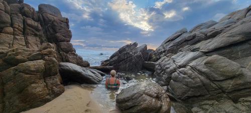 a person standing in the water on a rocky beach at OCEAN OASIS HOTEL - adult only, four casitas boutique resort in Playa Agua Blanca