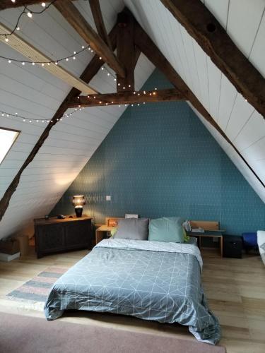 une chambre avec un grand lit dans un grenier dans l'établissement La parenthèse verte, à Meillac