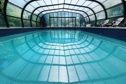 an indoor swimming pool with a glass ceiling at Splendide Château Napoléonien en Cévennes in Saint-Ambroix