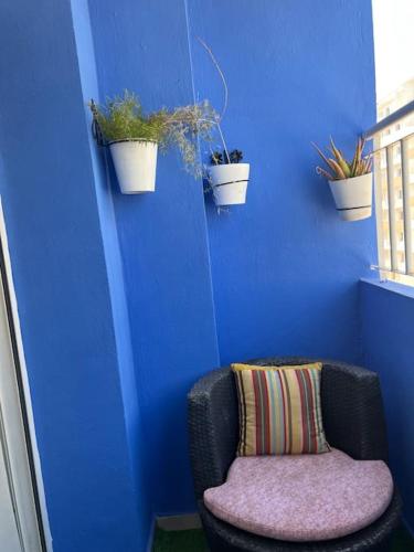 a blue wall with a chair and potted plants at Cozzy housse in Agadir