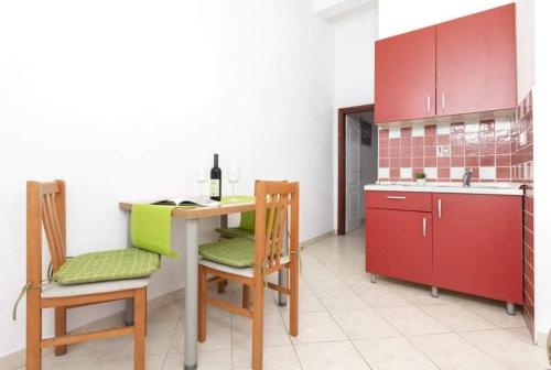 a kitchen with a table and chairs and red cabinets at Apartments Ljubica Tivat in Tivat