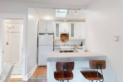 una cucina con armadi bianchi e un bancone con sgabelli di Madison Cottage a San Diego