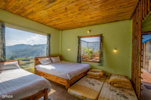 a bedroom with two beds and a large window at Stone Paradise Homestay in Sa Pa