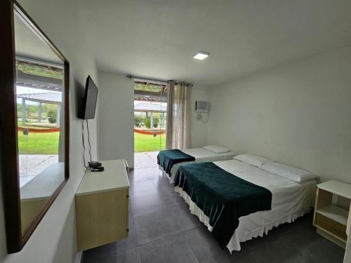 a hotel room with two beds and a television at Capri Hotel in São Francisco do Sul