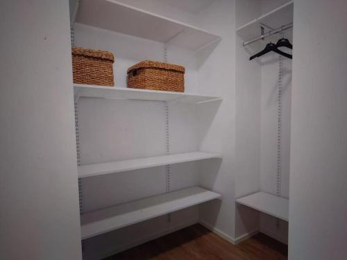 a walk in closet with white shelves and baskets at Uusi korkea tasoinen kaksio, ilmastointi in Turku