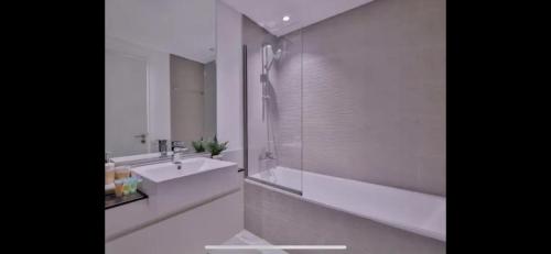 Modern Dublin City Centre في دبلن: حمام أبيض مع حوض وحوض استحمام ودش