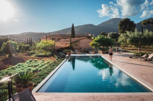a person walking by a swimming pool in a yard at Finca Es Cabàs in Santa Maria del Camí