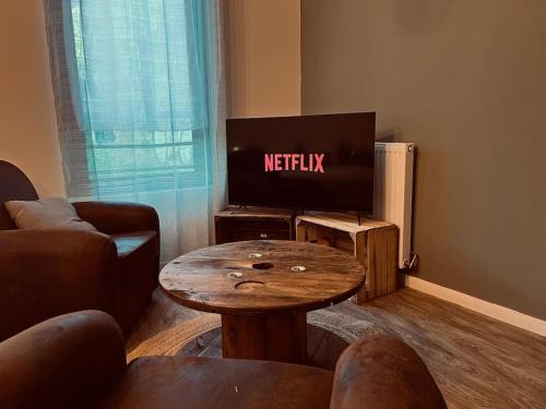 - un salon avec une télévision et une table en bois dans l'établissement Vinea urbana, à Dijon