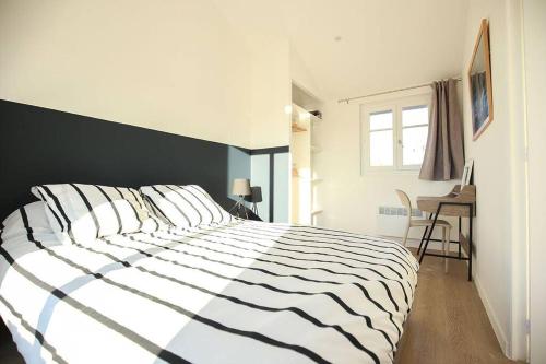 une chambre avec un lit avec une couette noire et blanche dans l'établissement Superbe Appartement Grande Terrasse vue Notre Dame, à Marseille