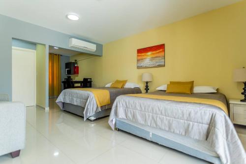 two beds in a room with yellow walls at Juanedu Suites in Oranjestad