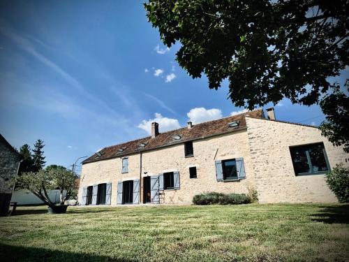a large white brick building with a grass yard at Le Clos de L'Olivier in Chaintreaux