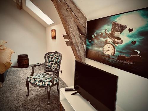 a room with a tv and a chair and a clock at Le Clos de L'Olivier in Chaintreaux