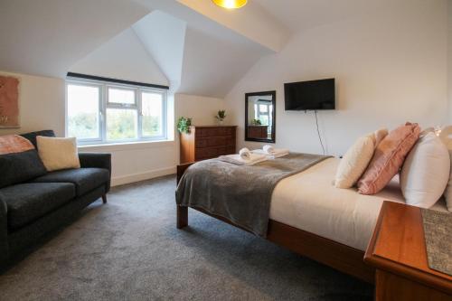 a bedroom with a bed and a couch and a television at Fairways View - Spacious Apartment - Sleeps 6 - Lovely Views in Hoylake