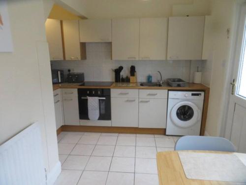 a kitchen with white cabinets and a washing machine at 29 Lewes Road - Darlington in Darlington