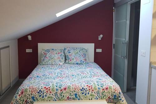 Ce lit se trouve dans une chambre dotée d'un mur rouge. dans l'établissement Acogedor apartamento nuevo en Puebla de Lillo, à Puebla de Lillo