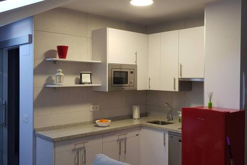 La cuisine est équipée de placards blancs et d'un réfrigérateur rouge. dans l'établissement Acogedor apartamento nuevo en Puebla de Lillo, à Puebla de Lillo