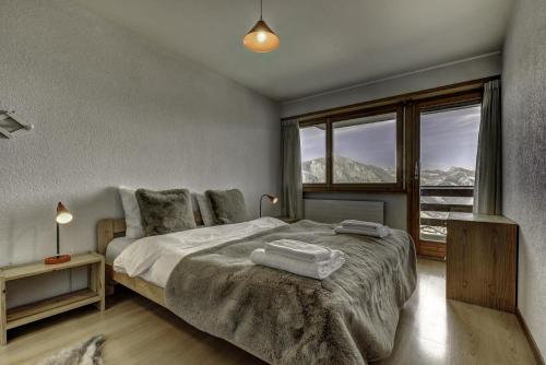 a bedroom with a bed and a large window at Appartement Mont Parrain 4 in La Tzoumaz