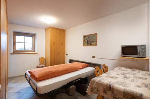 una stanza con un letto, un tavolo e una tv di Baita Francisi a Livigno
