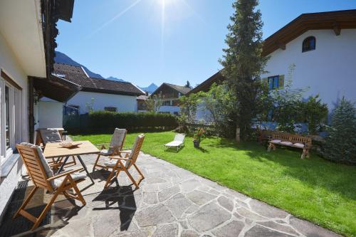 a patio with a table and chairs in a yard at Ferienwohnung zum Hirschgarten in Krün