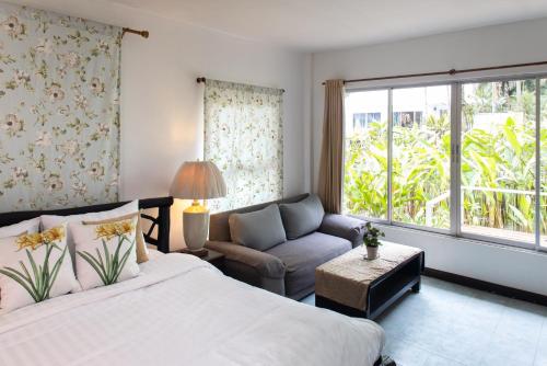 Baansook Resort Koh Chang في كو تشانغ: غرفة نوم بسرير واريكة ونافذة