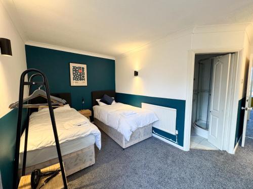 two beds in a room with green walls at Perfect for Contractors - Long Term Discounts, Free Parking & Fast Wifi in Wolverhampton