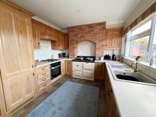 a kitchen with wooden cabinets and a brick wall at Perfect for Contractors - Long Term Discounts, Free Parking & Fast Wifi in Wolverhampton