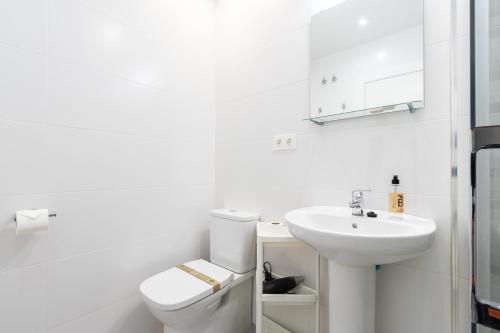Baño blanco con aseo y lavamanos en INSIDEHOME Apartments - La Casita de Irene en Palencia