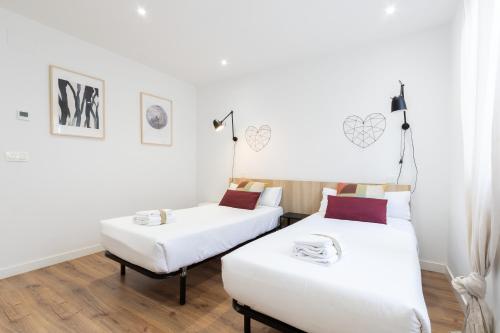 two beds in a room with white walls and wood floors at INSIDEHOME Apartments - La Casita de Irene in Palencia