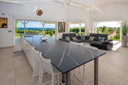 a kitchen and living room with a large black counter top at JADE - Villa Créole de Standing et de charme ,vue mer , proche des plages & piscine privée haut de gamme in Saint-François