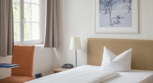 a bedroom with a bed and a chair and a window at Apartment Hotel Konstanz in Konstanz