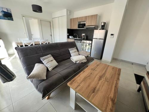 un salon avec un canapé noir et une table en bois dans l'établissement APPT 4 personnes TRIBORD, à Port-Leucate