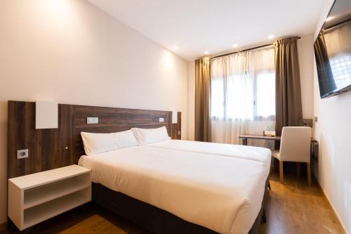 a bedroom with a large white bed and a desk at Alda Ruta Castilla in Palencia