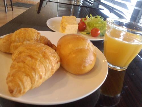 a plate of food with croissants and a glass of orange juice at APA Hotel Miyazaki Miyakonojo Ekimae in Miyakonozyō