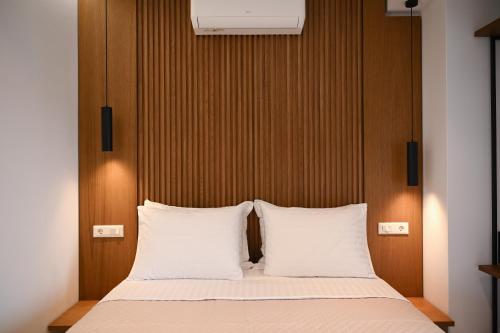 een bed met twee witte kussens en een houten hoofdeinde bij Athens Genesis Luxury Suites in Athene